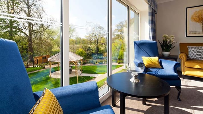 Bright living area with blue chairs and a view of the garden outside.