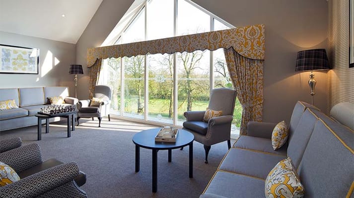 A spacious living room with comfortable seating and large windows overlooking greenery.