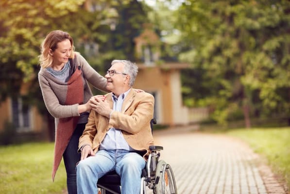 A caregiver assisting a resident in a wheelchair outdoors
