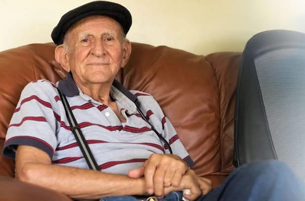 An elderly man sitting on a couch in a cozy setting