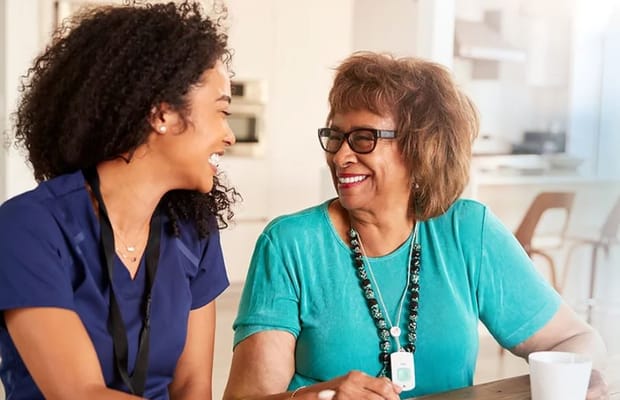 A caregiver and a resident smiling together in a common area