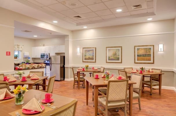 A well-set dining room with tables, chairs, and floral centerpieces.