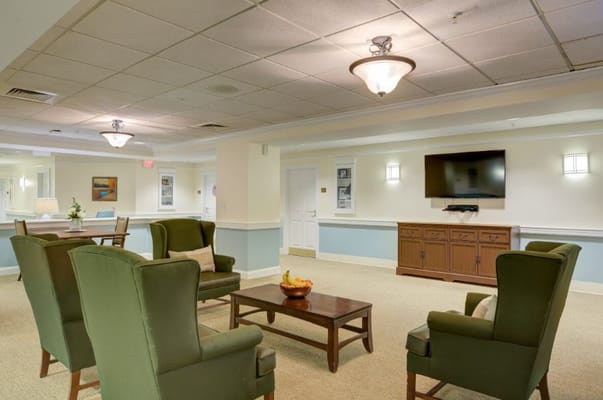 Seating area with green chairs and a coffee table in a senior living facility.