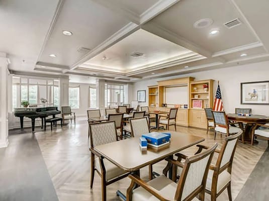 Bright common area with tables and chairs in a senior living facility