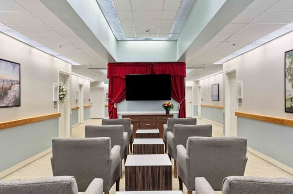 Lounge area with gray chairs and a TV at The Atrium at Veronica Drive