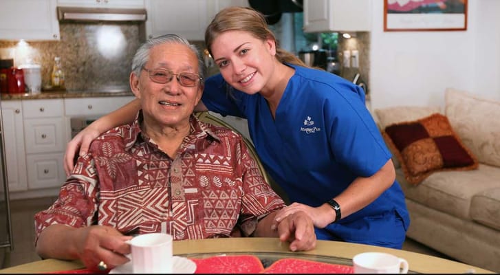 A caregiver and resident smiling together in a cozy lounge