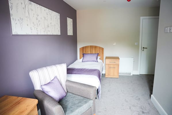 A well-furnished private resident room with gray and purple decor