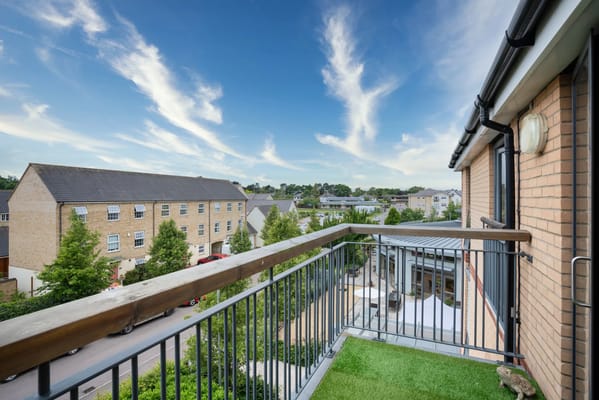 View from the balcony of Girton Green showcasing nearby houses and blue sky.