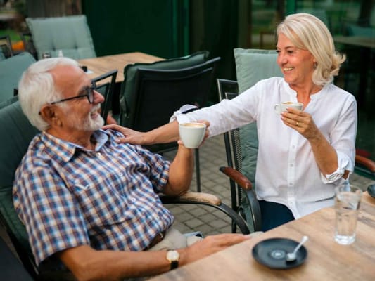 Two residents enjoying coffee outdoors on a patio
