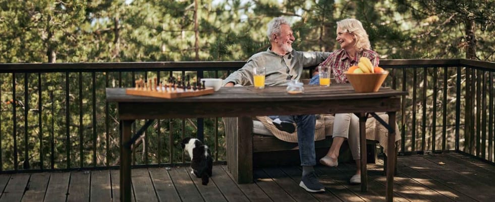 Two seniors enjoying drinks on an outdoor deck
