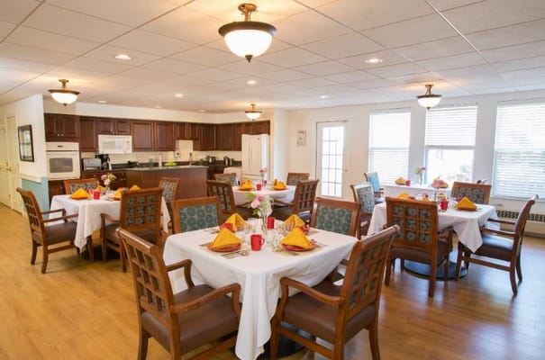 Brightly lit dining room with tables set for a meal.