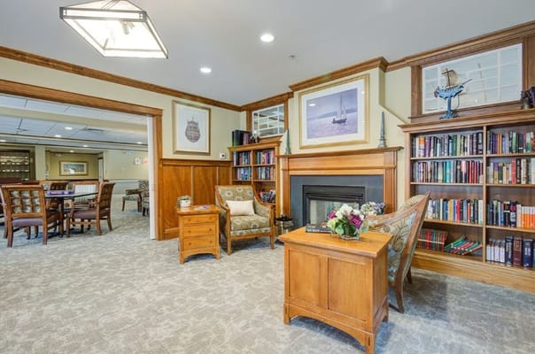 A cozy lounge with seating, bookshelves, and a fireplace.