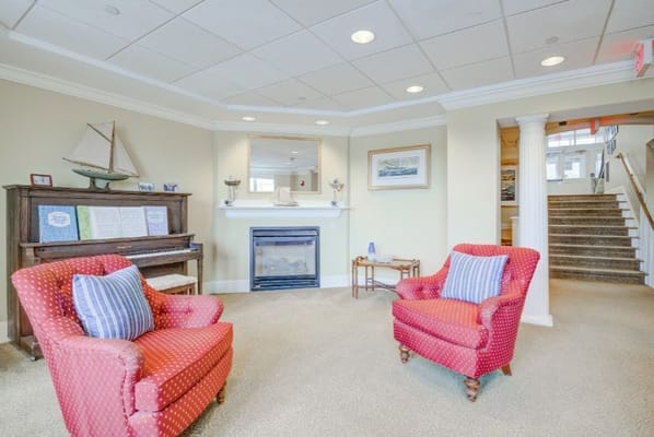 Living room with red chairs and piano at Academy Point at Mystic