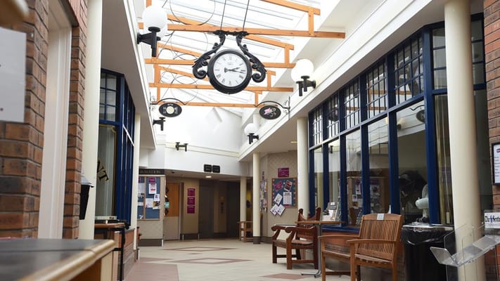 A spacious hallway featuring a large clock and seating areas.