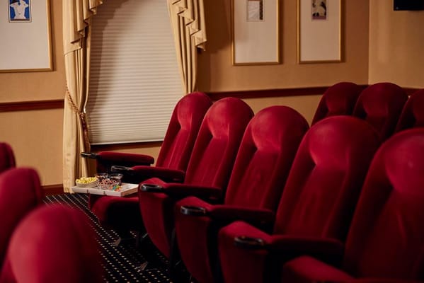 Red plush theater seats with snacks on a table