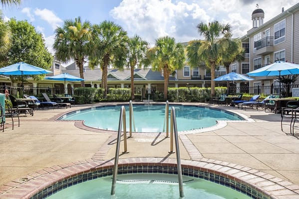 Outdoor pool area with lounging space and palm trees