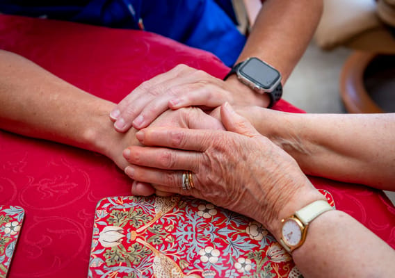 Hands of a caregiver and a senior holding each other