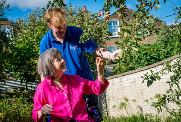 Resident enjoying fruit picking in the garden with staff