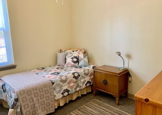 A cozy private resident room with a bed and lamp