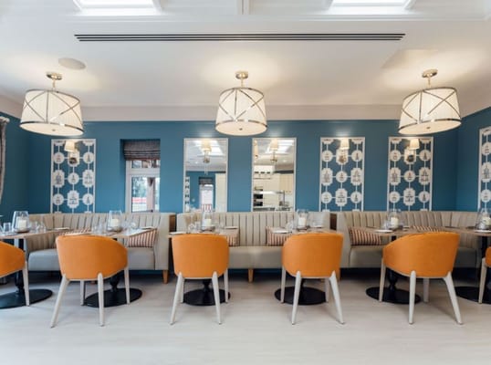 Bright dining area with orange chairs and blue wall