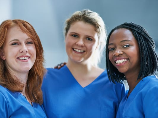 Three staff members smiling in scrubs