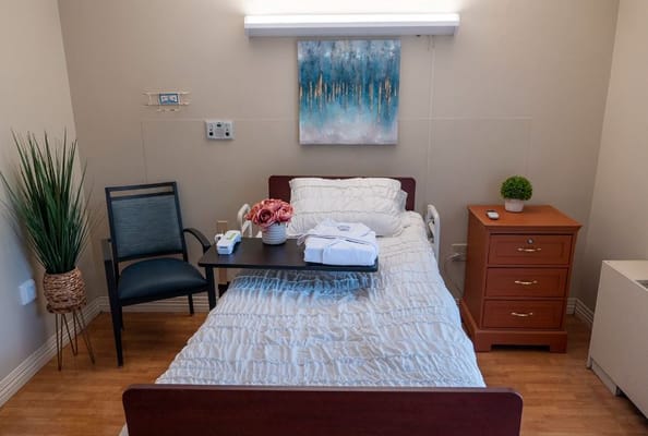 A well-furnished private resident room with a bed and chair