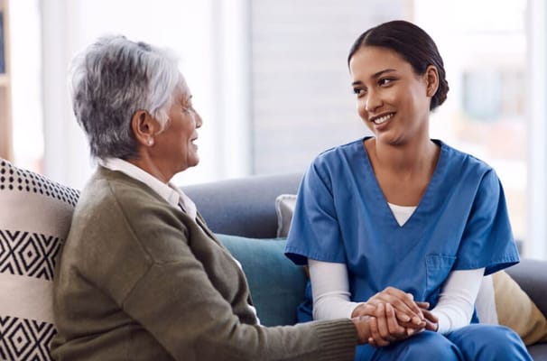 A caregiver and senior resident smiling and holding hands