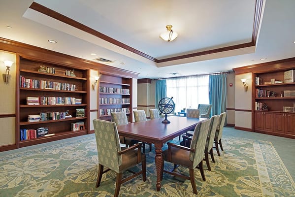 A nicely appointed common area with bookshelves and a large table