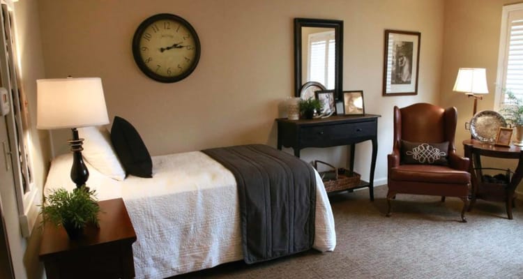 A well-appointed bedroom featuring a bed, a clock, and a comfortable chair.