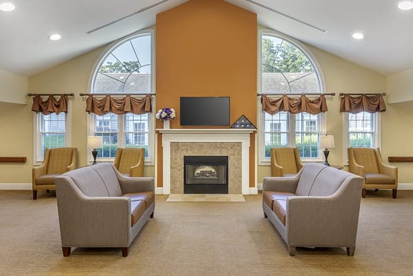 A cozy common area with seating around a fireplace