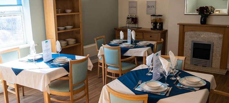 Well-set dining tables with blue tablecloths and decorative menus.