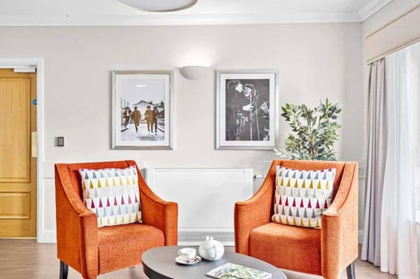 Bright seating area with orange chairs and framed artwork