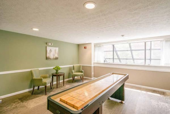 Shuffleboard table with seating area in a bright common space