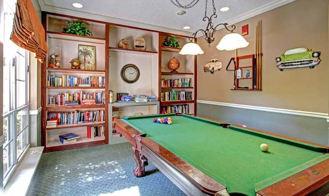 A pool table in a cozy lounge area with bookshelves.