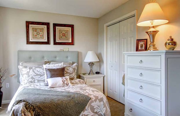 A well-decorated bedroom with a bed, lamp, and dresser.