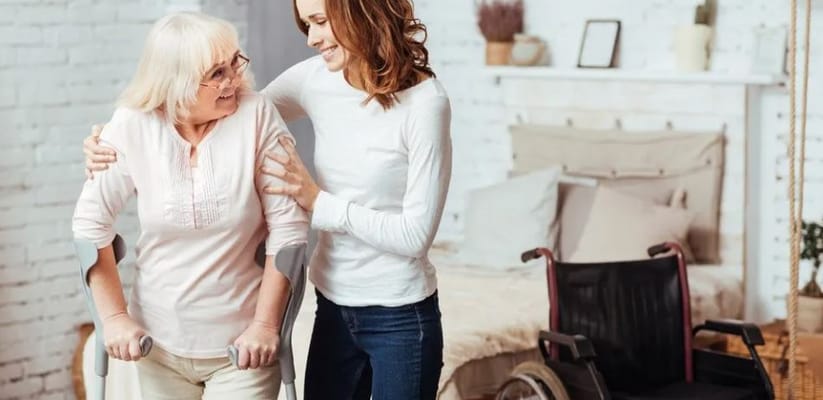 A caregiver assisting a senior woman in a cozy room