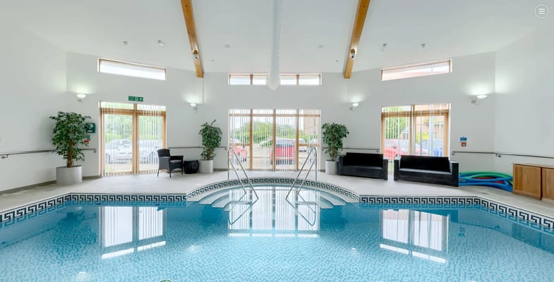 Indoor swimming pool with seating and plants at Girton Green