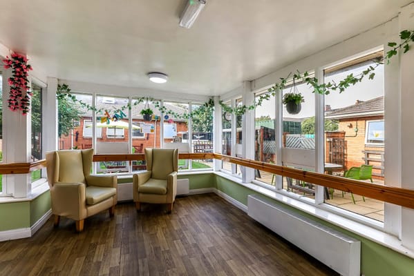 Bright sunroom with two chairs and greenery