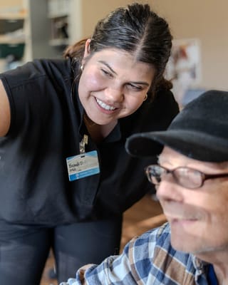 A caregiver smiling and assisting an elderly resident.