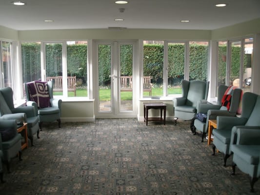 Spacious sitting area with green chairs and large windows
