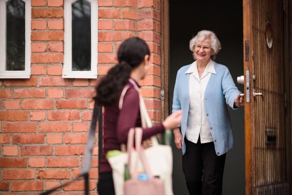 A smiling resident greeting a staff member at the door