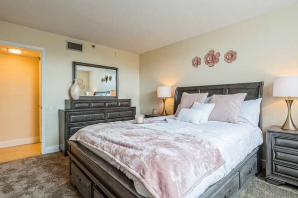 Spacious bedroom with a queen bed, dresser, and decorative accents.