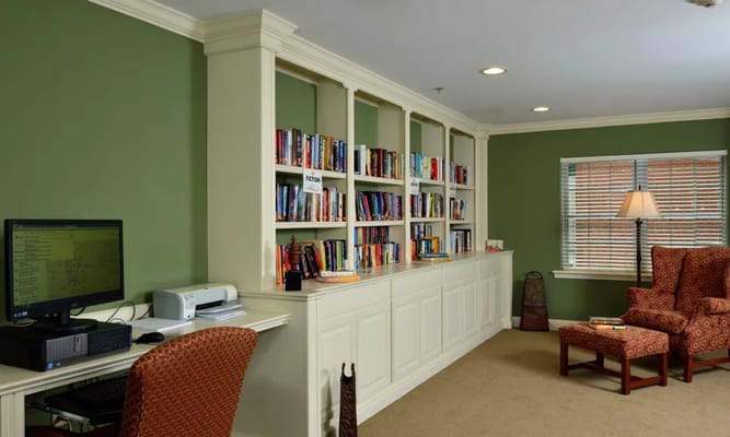 A library area featuring bookshelves, a computer station, and comfortable seating.