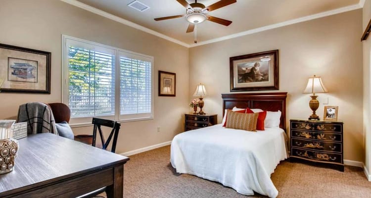 A well-decorated bedroom with a bed, desk, and soft lighting.