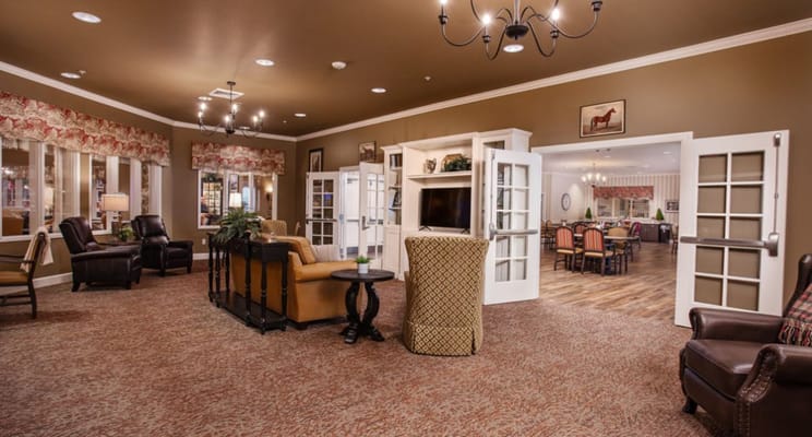 Lounge area with seating and large windows in Deer Ridge Memory Care Community.
