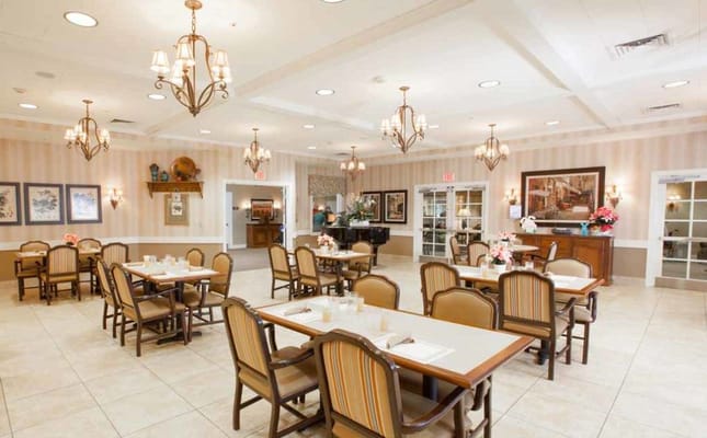 Brightly lit dining room with tables and chairs set for meals.
