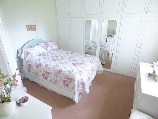 A cozy bedroom with floral bedding and mirrored closet