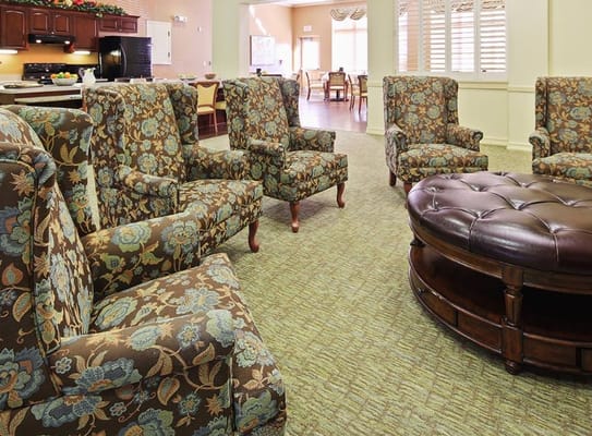 Comfortable floral chairs surrounding a round coffee table in a lounge area.