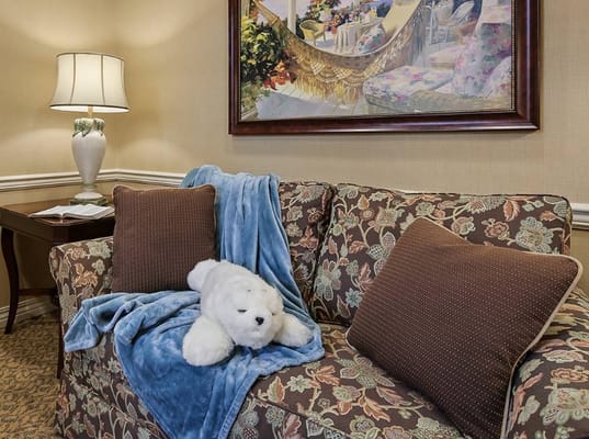 A plush couch with decorative pillows, a blue blanket, and a stuffed animal in a welcoming living room.