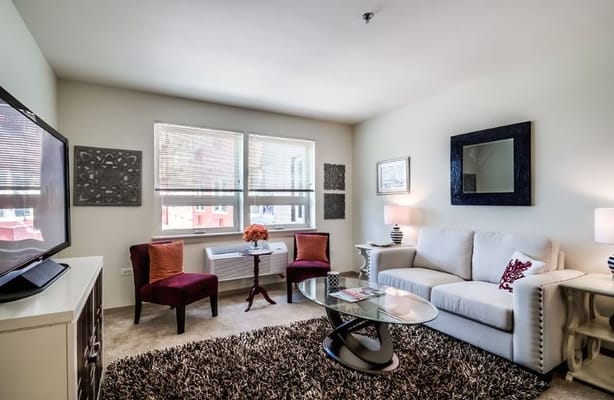 Living room with a sofa, chairs, and television in Senior Suites of Bellwood.